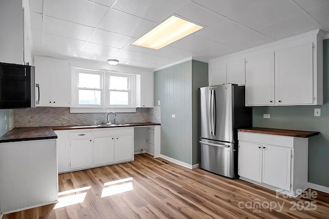 kitchen featuring a sink, white cabinets, light wood-style floors, appliances with stainless steel finishes, and dark countertops