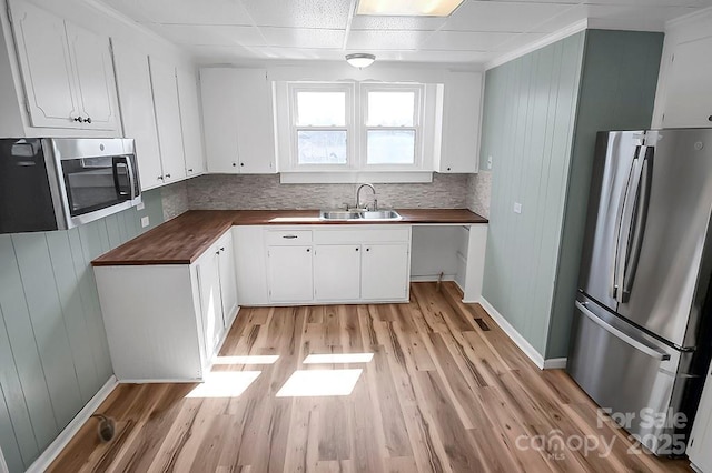 kitchen featuring butcher block counters, a sink, white cabinetry, appliances with stainless steel finishes, and light wood finished floors