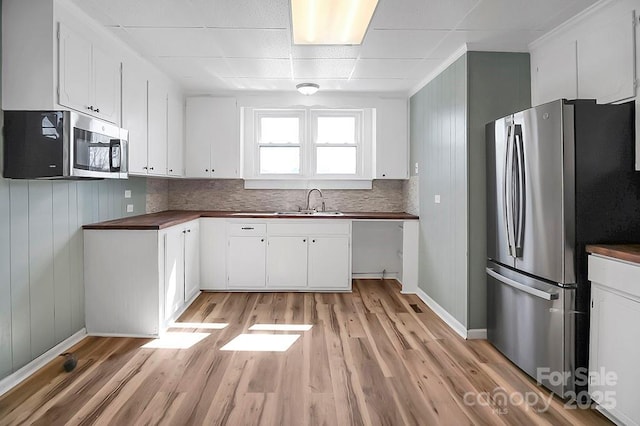 kitchen with stainless steel appliances, a sink, white cabinetry, and light wood-style floors