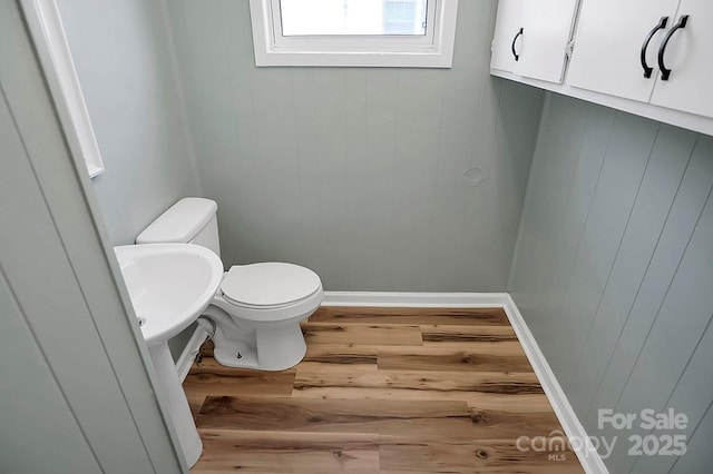 bathroom with wood finished floors, toilet, and baseboards