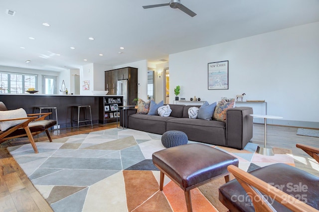 living area with ceiling fan, light wood finished floors, visible vents, and recessed lighting