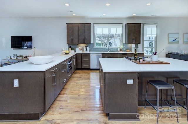 kitchen with light countertops, appliances with stainless steel finishes, a peninsula, and dark brown cabinetry