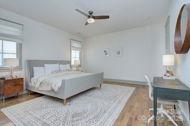 bedroom with light wood finished floors, a ceiling fan, and baseboards