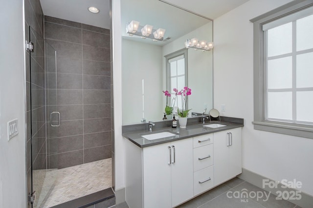 bathroom with double vanity, a stall shower, a sink, and tile patterned floors