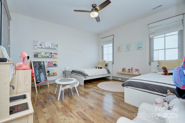 bedroom featuring ceiling fan, visible vents, and wood finished floors