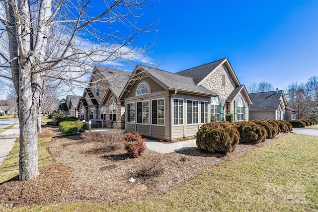 view of side of home with a yard and roof with shingles