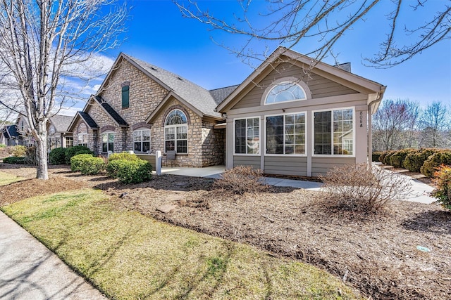 view of front of house with stone siding and a patio area