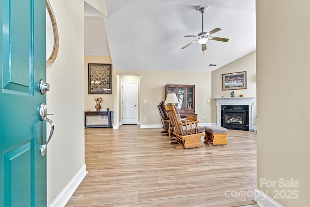 entryway with light wood-style flooring, vaulted ceiling, a ceiling fan, and a high end fireplace