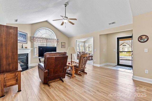 living area with a wealth of natural light, light wood finished floors, and a premium fireplace