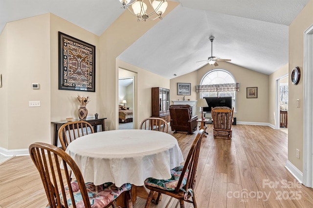 dining space with baseboards, vaulted ceiling, light wood finished floors, and ceiling fan with notable chandelier