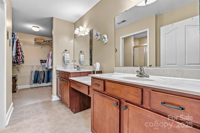 bathroom featuring a stall shower, visible vents, tile patterned floors, a spacious closet, and vanity