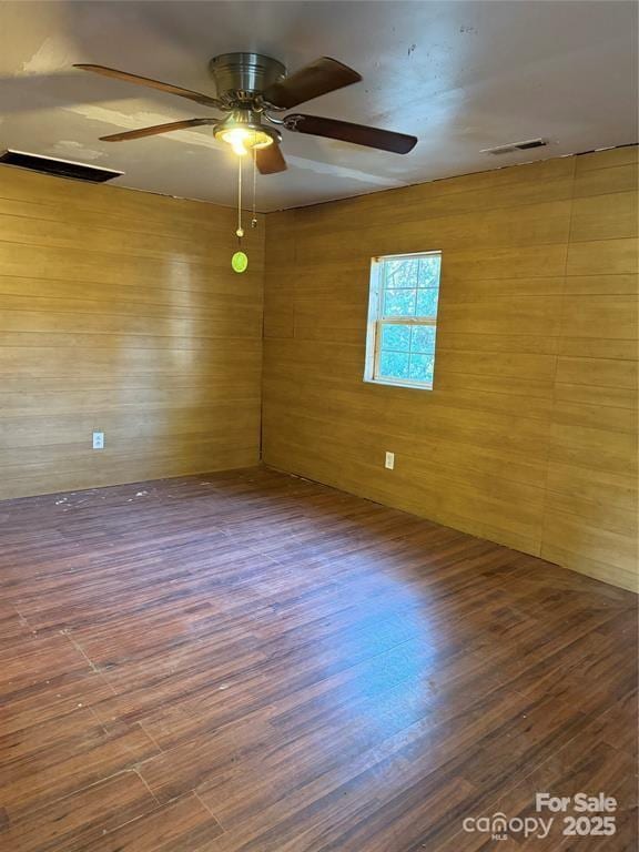 empty room featuring a ceiling fan, visible vents, and wood finished floors