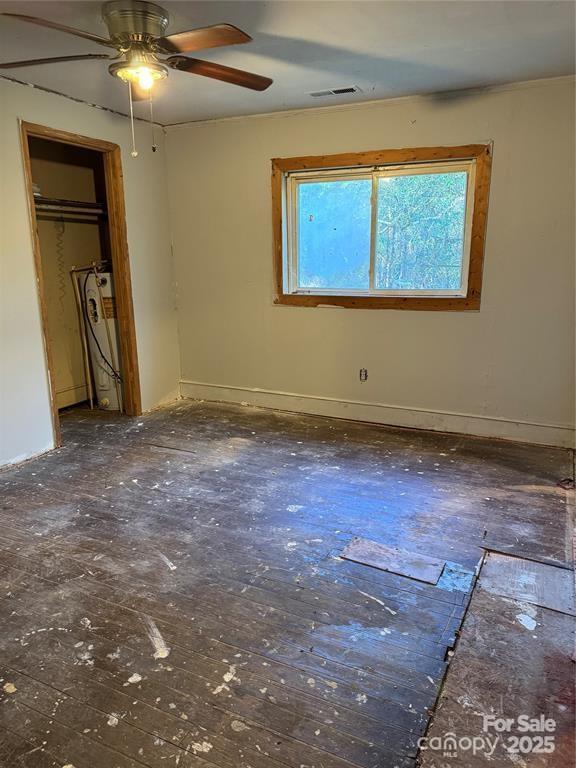 unfurnished bedroom featuring water heater, a ceiling fan, visible vents, and baseboards