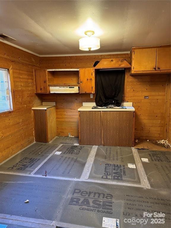 kitchen with brown cabinets, visible vents, and wooden walls