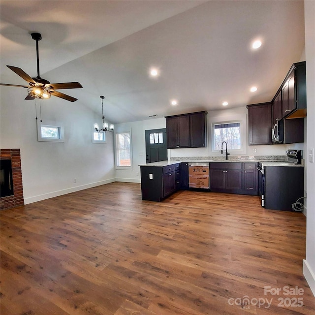 kitchen with electric stove, lofted ceiling, open floor plan, wood finished floors, and a peninsula