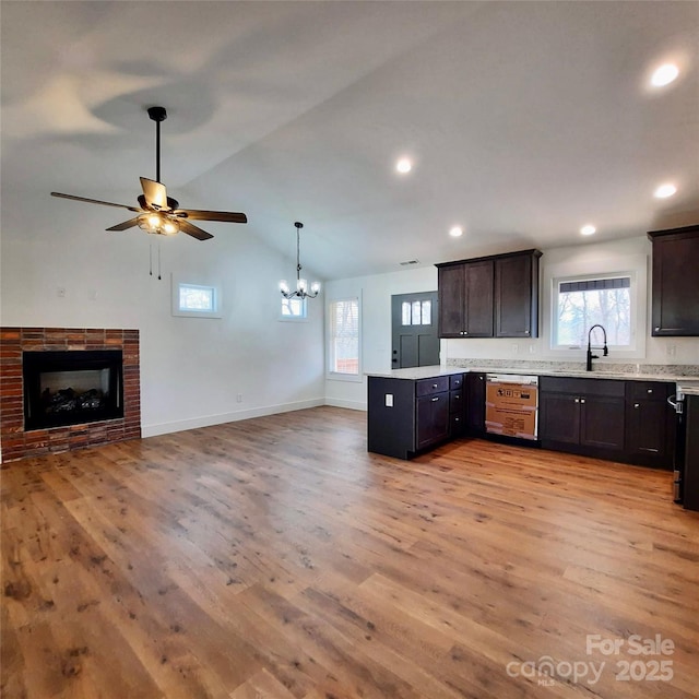 kitchen with open floor plan, vaulted ceiling, a fireplace, and light wood-style floors