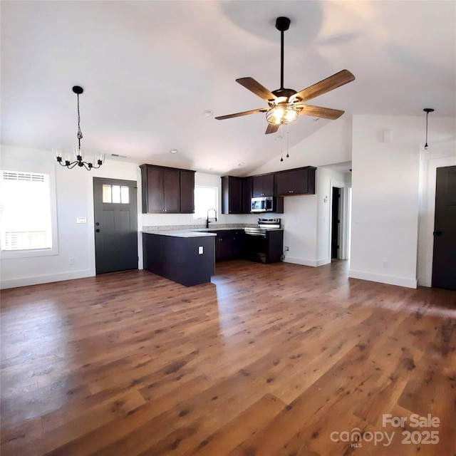 kitchen with light countertops, stainless steel microwave, open floor plan, a sink, and wood finished floors