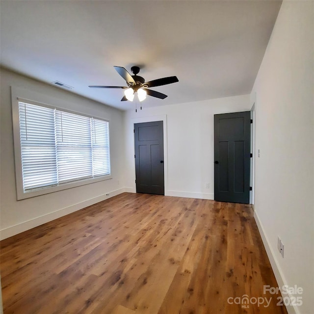 unfurnished bedroom featuring baseboards, visible vents, and wood finished floors