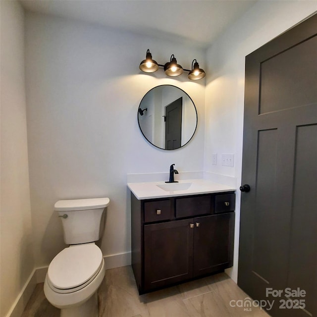 half bathroom featuring toilet, baseboards, and vanity