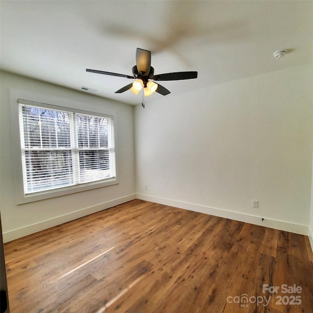 spare room featuring ceiling fan, wood finished floors, visible vents, and baseboards