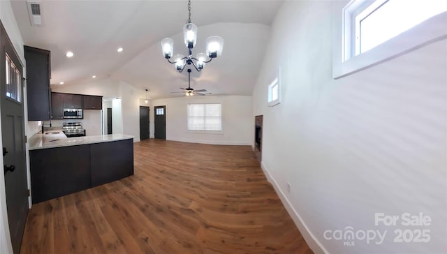 kitchen with decorative light fixtures, stainless steel appliances, dark wood-type flooring, a sink, and a peninsula