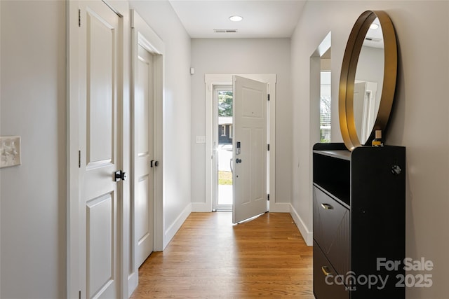 foyer entrance featuring baseboards, visible vents, light wood-style flooring, and a healthy amount of sunlight