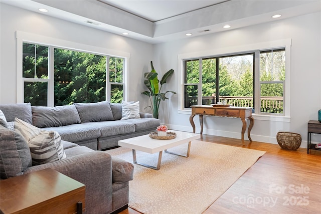 living room featuring visible vents, baseboards, wood finished floors, and recessed lighting