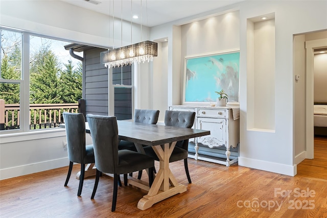 dining room with baseboards, light wood finished floors, and an inviting chandelier