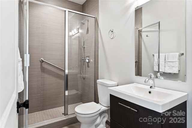 bathroom featuring toilet, a shower stall, and vanity