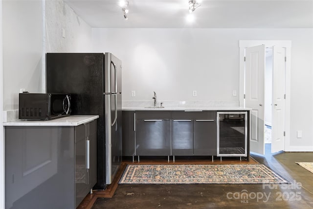 kitchen with beverage cooler, light countertops, concrete flooring, black microwave, and a sink