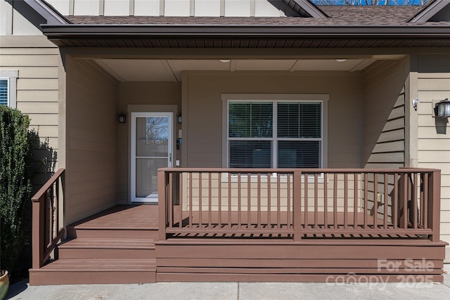 doorway to property featuring a porch and roof with shingles