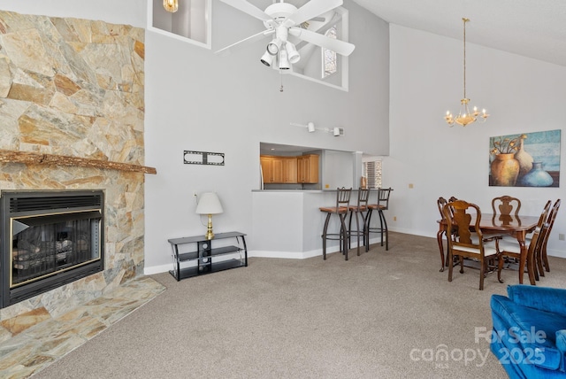 carpeted living area with ceiling fan with notable chandelier, high vaulted ceiling, a fireplace, and baseboards