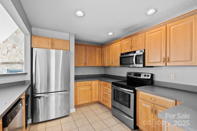 kitchen featuring dark countertops, light tile patterned flooring, stainless steel appliances, a textured ceiling, and recessed lighting