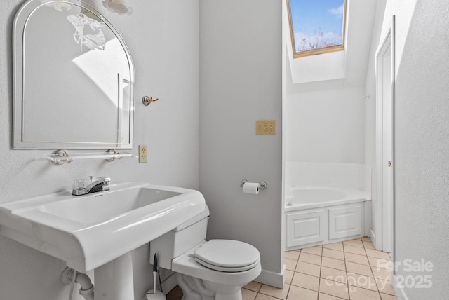 full bath featuring baseboards, toilet, a bath, tile patterned floors, and a sink