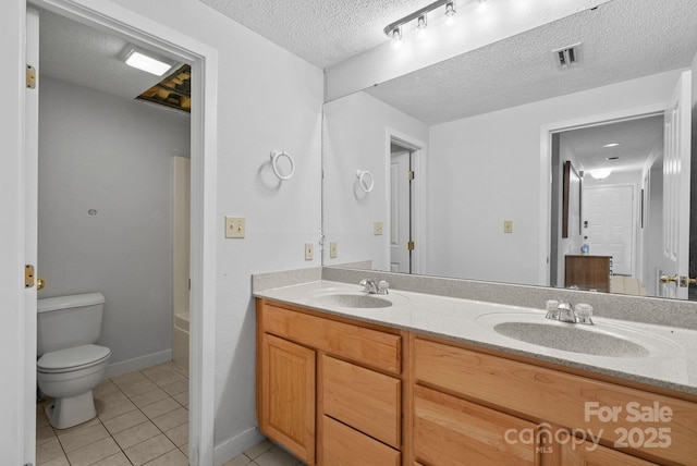 bathroom featuring tile patterned flooring, visible vents, a sink, and a textured ceiling