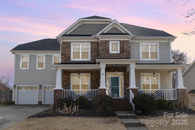 craftsman house featuring driveway, a garage, stone siding, roof with shingles, and a porch