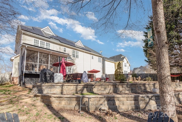 back of house with solar panels, a patio area, fence, and a sunroom