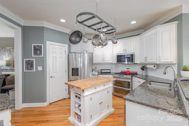 kitchen with white cabinetry, appliances with stainless steel finishes, wooden counters, and a sink