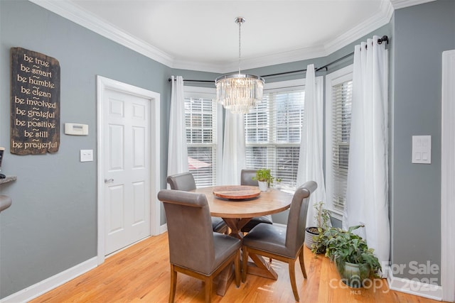 dining room with light wood-style floors, a notable chandelier, baseboards, and crown molding