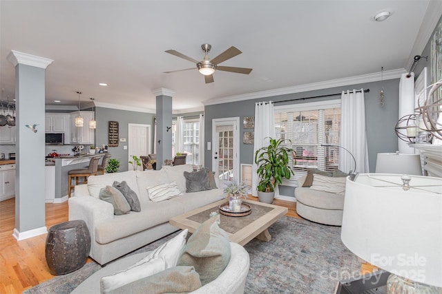 living room featuring a ceiling fan, ornamental molding, and light wood-style flooring