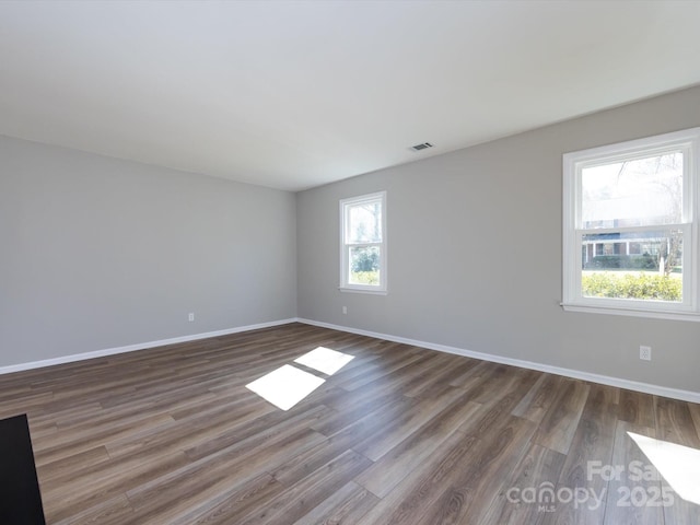 spare room with visible vents, baseboards, and wood finished floors