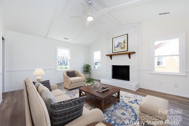 living room featuring visible vents, a fireplace, lofted ceiling with beams, and wood finished floors