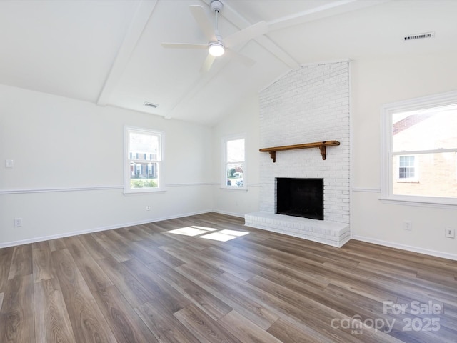 unfurnished living room with visible vents, beamed ceiling, a fireplace, and wood finished floors