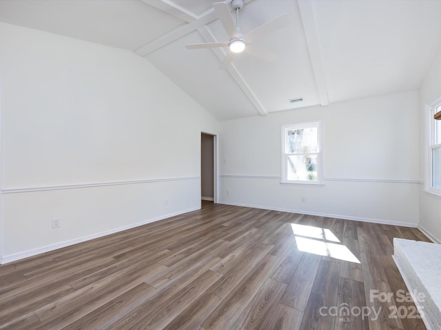 spare room featuring visible vents, vaulted ceiling with beams, wood finished floors, and baseboards