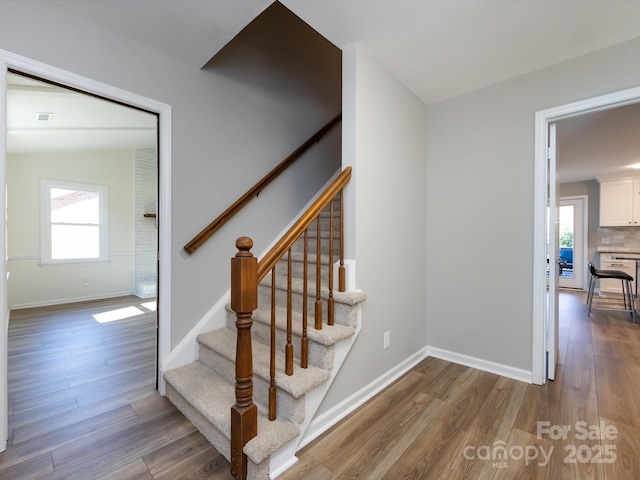 stairs with plenty of natural light, baseboards, and wood finished floors