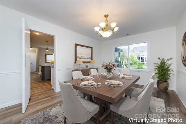 dining room with baseboards, visible vents, light wood finished floors, and a chandelier