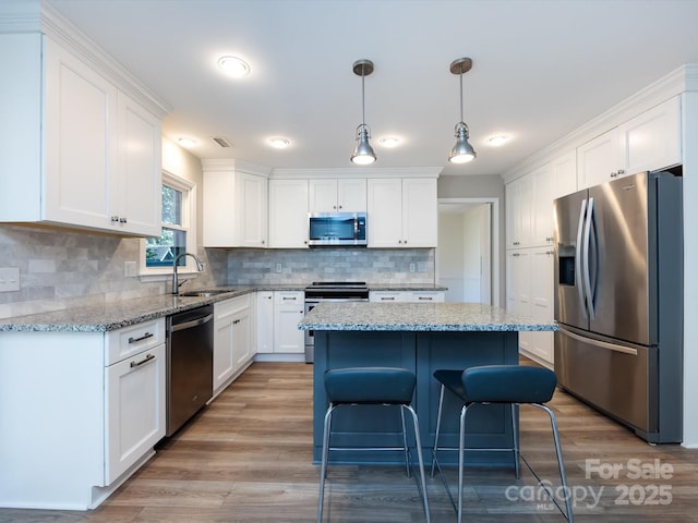 kitchen with backsplash, a center island, stainless steel appliances, white cabinetry, and a sink