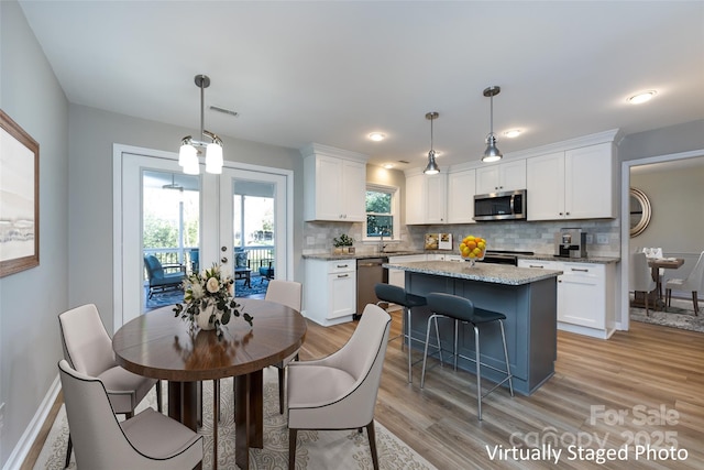 dining room featuring visible vents, light wood-style floors, baseboards, and french doors