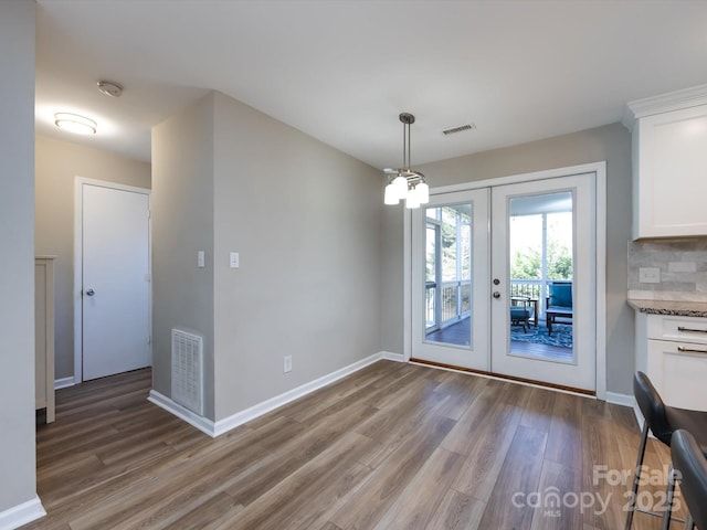 unfurnished dining area with light wood finished floors, visible vents, french doors, and baseboards