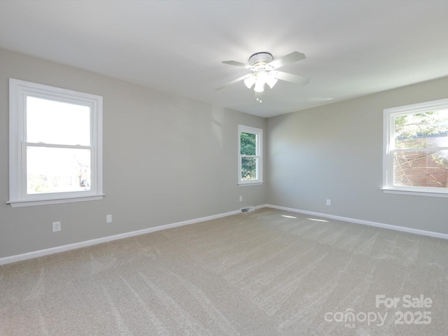 empty room featuring a ceiling fan, baseboards, a wealth of natural light, and light carpet